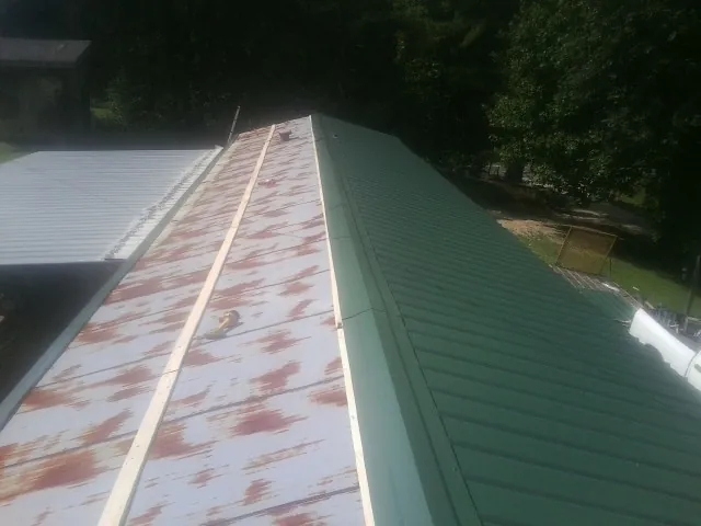 Old rusted panels beside newly installed green metal roofing — Wind Damage Roof Repair by Roofing Brothers in Birchwood
