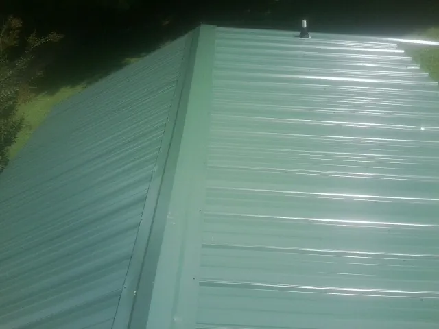 New green metal panels meeting at the ridge of a roof — Flat Roof Repair work by our crew in Birchwood