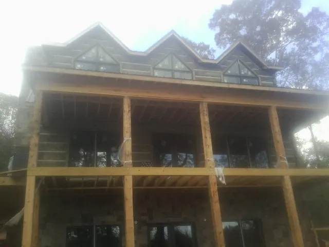 Dormers and porch framing on a large log home under construction — Roof Coating work by our crew in Birchwood