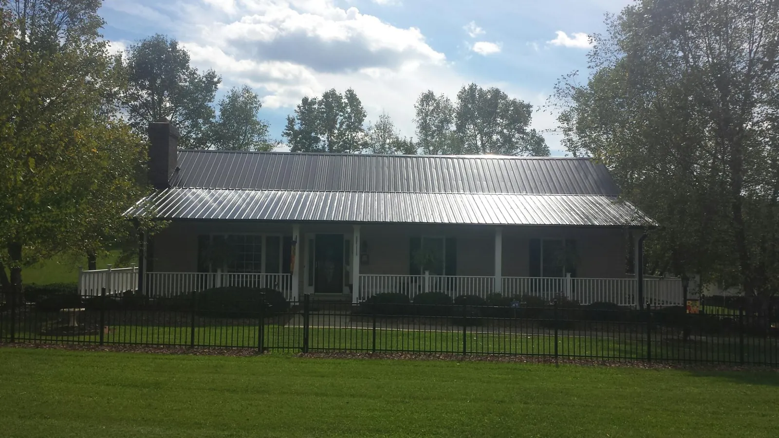 Gray metal roof on a brick ranch with a full width front porch — Gutter Guard Installation work by our crew in Birchwood