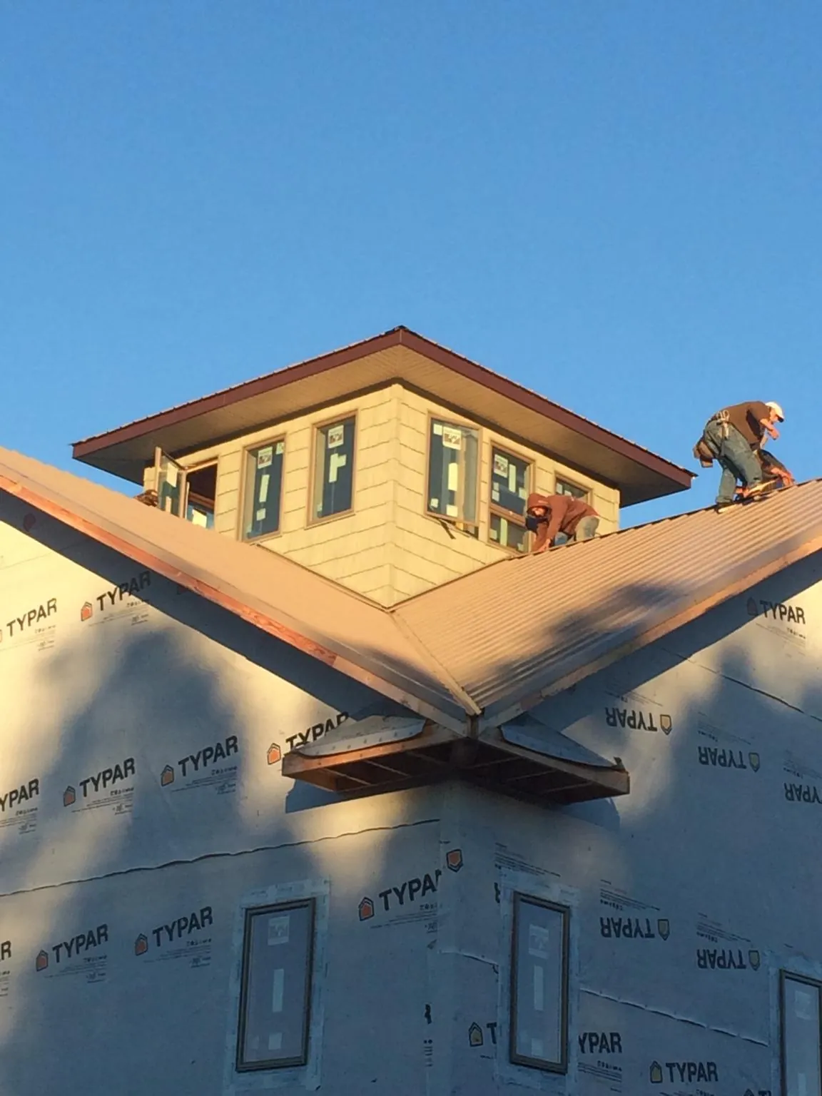 Roofers working around a rooftop cupola on a new metal roof at sunset — Roof Waterproofing in Birchwood by Roofing Brothers